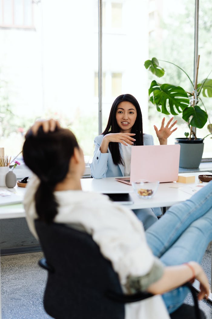Two women engaging in a collaborative conversation at a modern office with natural lighting.